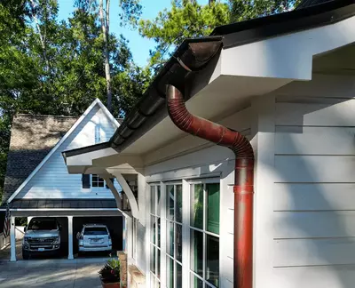 Copper half-round gutter system from GutterPro with collector heads installed on a white brick home.