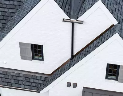 GutterPro's black half-round gutter system is installed on this white brick home to deliver a perfect blend of modern style and effective drainage.