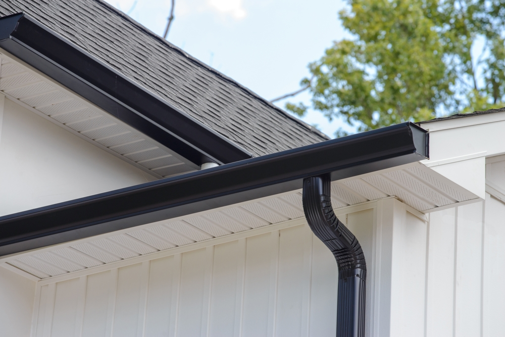 shiny black gutters and downspout on white house