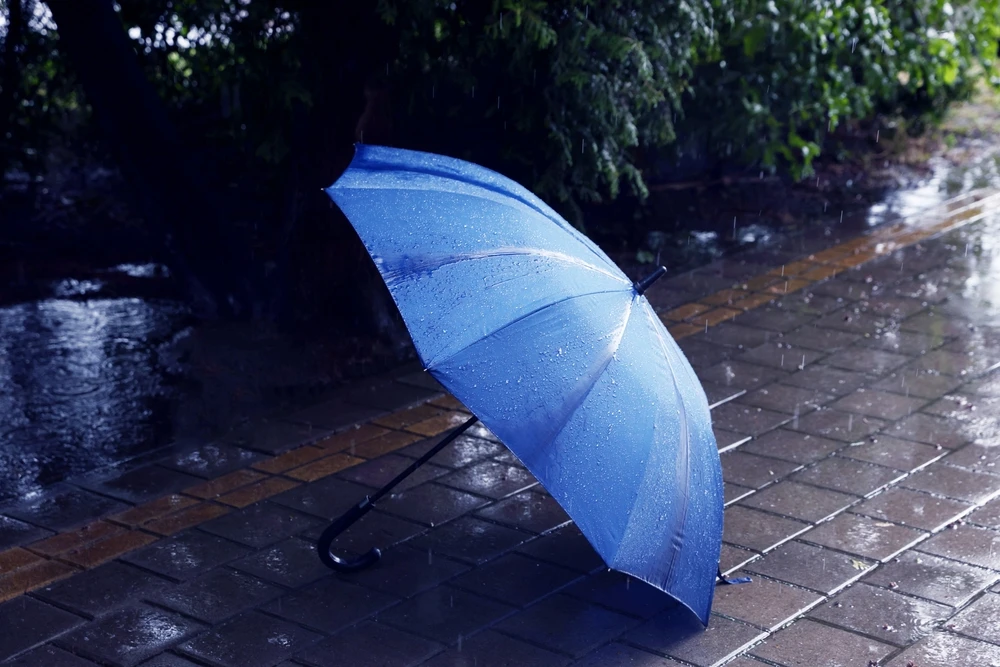 blue umbrella on sidewalk in heavy rain
